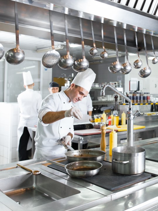 Koch in Restaurantküche mit leistungsstarker Abzugsanlage